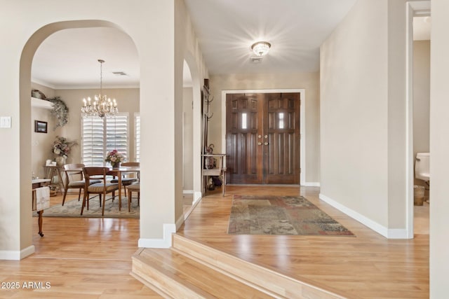 entryway featuring a chandelier, visible vents, baseboards, and wood finished floors