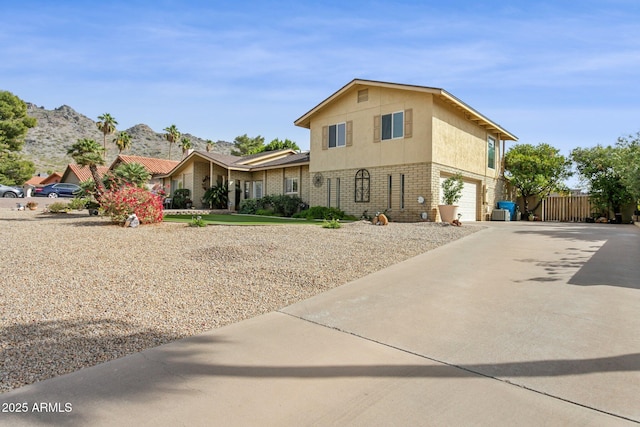 view of front of home featuring a mountain view, a garage, brick siding, fence, and driveway