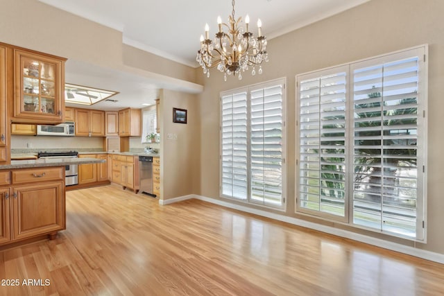 kitchen featuring light wood-style flooring, baseboards, stainless steel appliances, and crown molding