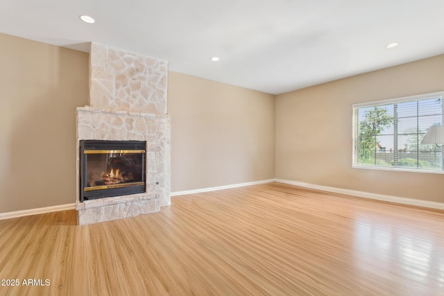 unfurnished living room featuring recessed lighting, a fireplace, wood finished floors, and baseboards