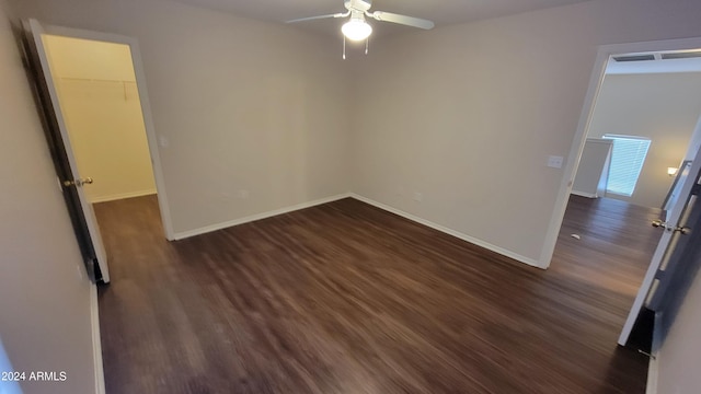 interior space featuring ceiling fan, dark wood-type flooring, a walk in closet, and a closet