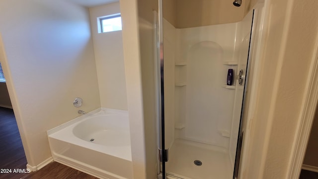 bathroom featuring hardwood / wood-style flooring and plus walk in shower