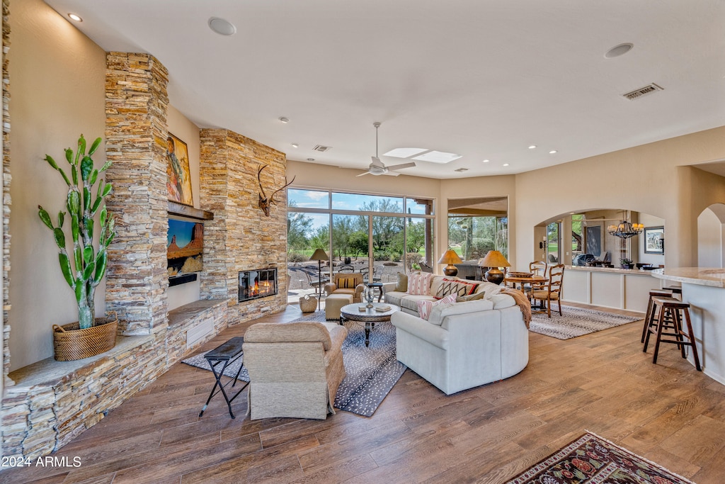 living room with a fireplace, hardwood / wood-style floors, and ceiling fan with notable chandelier