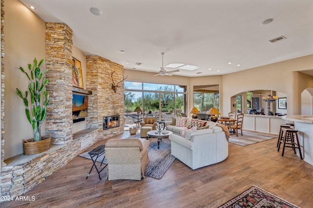 living room with a fireplace, hardwood / wood-style floors, and ceiling fan with notable chandelier