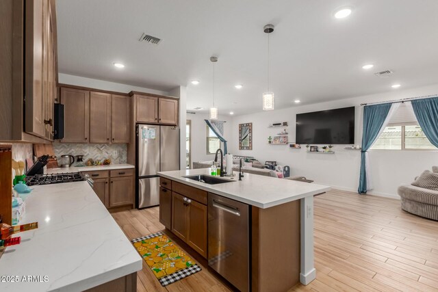 kitchen featuring visible vents, appliances with stainless steel finishes, a sink, light wood finished floors, and open floor plan
