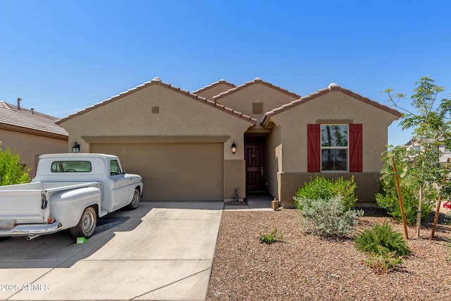 view of front facade with a tiled roof, a garage, stucco siding, and driveway