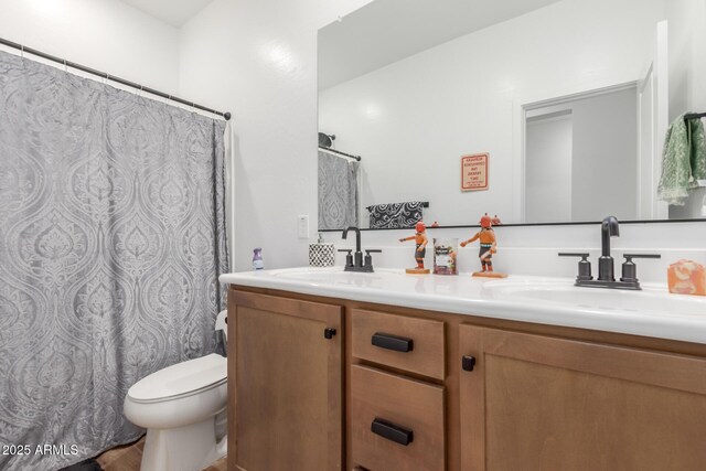 full bathroom with double vanity, toilet, curtained shower, and a sink