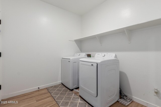 washroom with baseboards, laundry area, washing machine and dryer, and light wood-style flooring