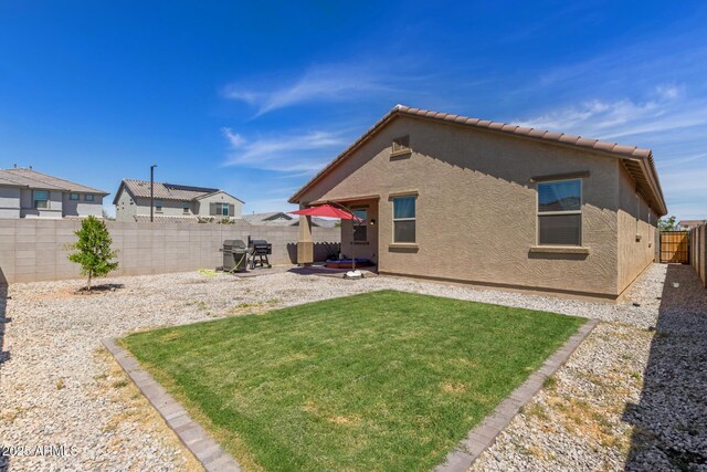 rear view of property featuring a tiled roof, a patio area, a fenced backyard, a yard, and stucco siding
