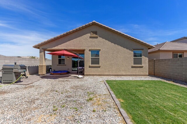 rear view of house featuring a lawn, a patio, a fenced backyard, and stucco siding