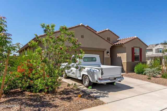 mediterranean / spanish house featuring an attached garage, driveway, a tile roof, and stucco siding