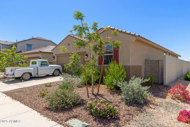 exterior space with stucco siding, a tiled roof, driveway, and a garage