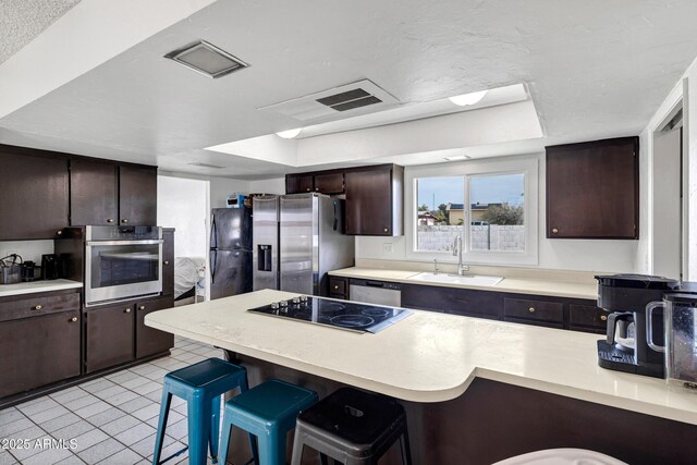 3222 W Hearn Rd, Phoenix, AZ 85053 - kitchen with dark brown cabinets, a breakfast bar, light countertops, black appliances, and a sink