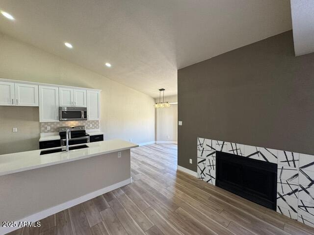 5236 W Peoria Ave Unit 232, Glendale, AZ 85302 - kitchen featuring stainless steel appliances, tasteful backsplash, light countertops, lofted ceiling, and wood finished floors