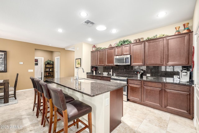 kitchen with a kitchen breakfast bar, backsplash, visible vents, appliances with stainless steel finishes, and a sink