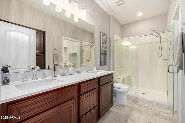 bathroom featuring a sink, a stall shower, toilet, and double vanity