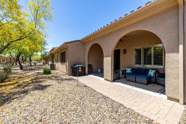 rear view of property featuring an outdoor hangout area, stucco siding, a patio area, central air condition unit, and a tiled roof