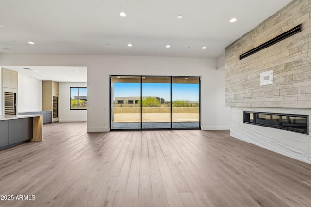 13278 E Buckskin Trl, Scottsdale, AZ 85255 - unfurnished living room featuring a fireplace, baseboards, light wood-style floors, wine cooler, and recessed lighting