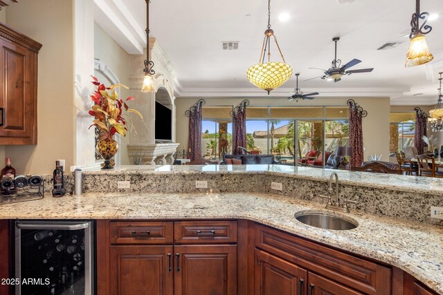 18036 W San Miguel Ave, Litchfield Park, AZ 85340 - kitchen featuring wine cooler, a ceiling fan, a sink, light stone counters, and ornamental molding
