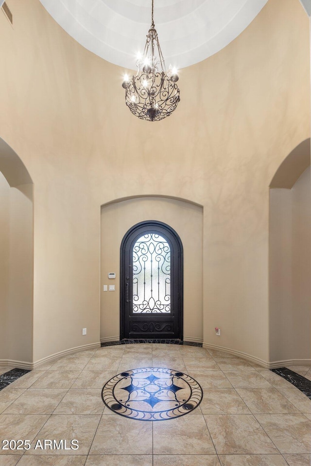 18036 W San Miguel Ave, Litchfield Park, AZ 85340 - foyer entrance with arched walkways, a high ceiling, a chandelier, inlaid floor details, and baseboards