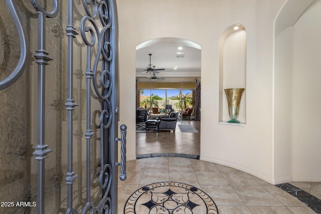 18036 W San Miguel Ave, Litchfield Park, AZ 85340 - foyer entrance with inlaid floor details, ceiling fan, light tile patterned floors, baseboards, and arched walkways