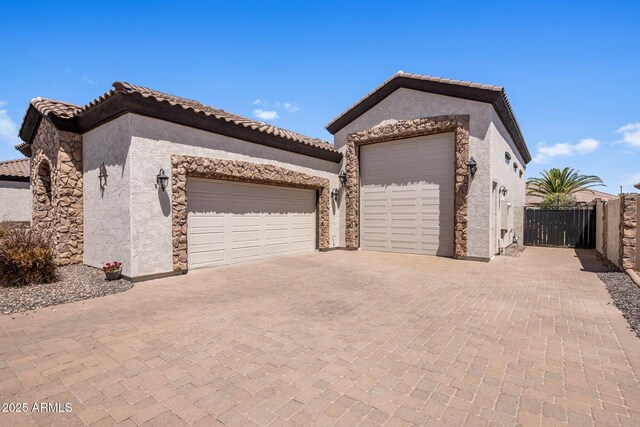 18036 W San Miguel Ave, Litchfield Park, AZ 85340 - view of front of home with an attached garage, stucco siding, decorative driveway, a tiled roof, and stone siding