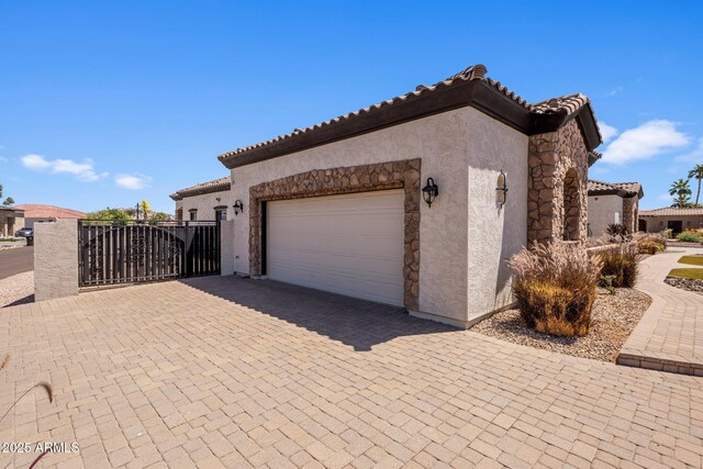 18036 W San Miguel Ave, Litchfield Park, AZ 85340 - view of property exterior with stucco siding, a garage, decorative driveway, a tile roof, and a gate