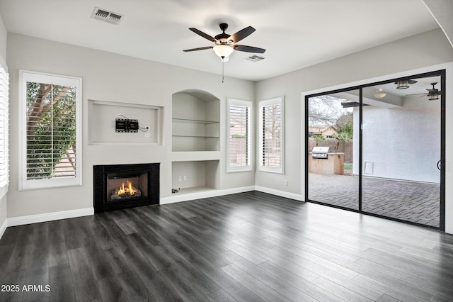 1612 E Zion Way, Chandler, AZ 85249 - unfurnished living room featuring ceiling fan, a wealth of natural light, dark wood-type flooring, and built in shelves