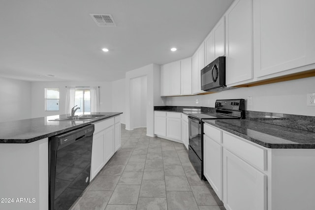 kitchen featuring sink, white cabinets, dark stone counters, a kitchen island with sink, and black appliances