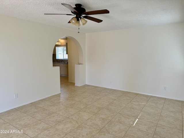 tiled spare room featuring a textured ceiling and ceiling fan