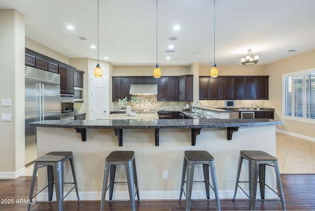 5243 E Windstone Trl, Cave Creek, AZ 85331 - kitchen with appliances with stainless steel finishes, range hood, dark brown cabinetry, decorative backsplash, and recessed lighting