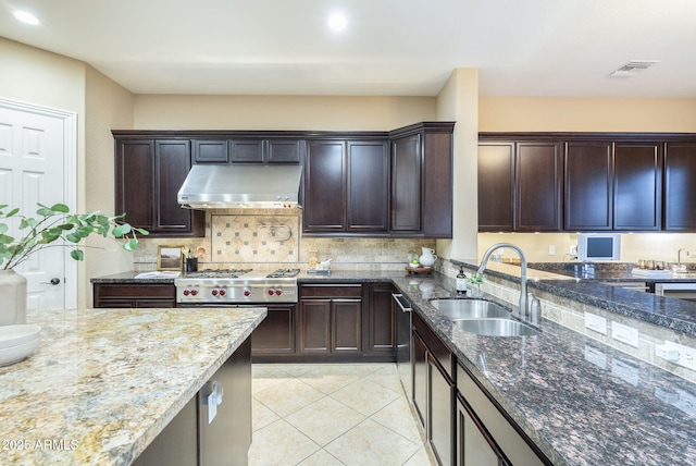 5243 E Windstone Trl, Cave Creek, AZ 85331 - kitchen with under cabinet range hood, stainless steel gas stovetop, dark stone counters, light tile patterned floors, and tasteful backsplash