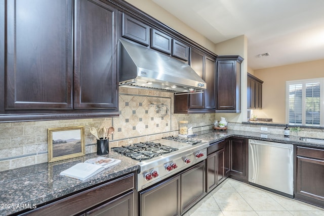 5243 E Windstone Trl, Cave Creek, AZ 85331 - kitchen with appliances with stainless steel finishes, under cabinet range hood, dark brown cabinets, dark stone countertops, and tasteful backsplash