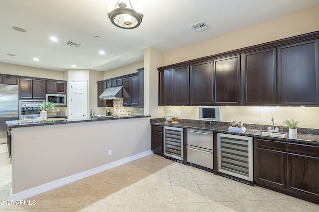 5243 E Windstone Trl, Cave Creek, AZ 85331 - kitchen with beverage cooler, built in appliances, under cabinet range hood, dark stone counters, and recessed lighting