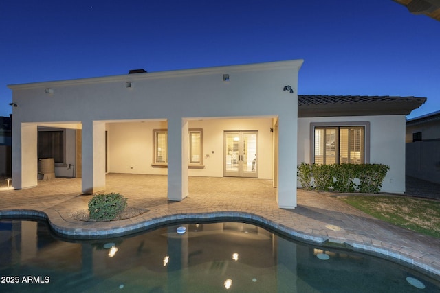 5243 E Windstone Trl, Cave Creek, AZ 85331 - back of house at night with a patio area, an outdoor pool, and stucco siding