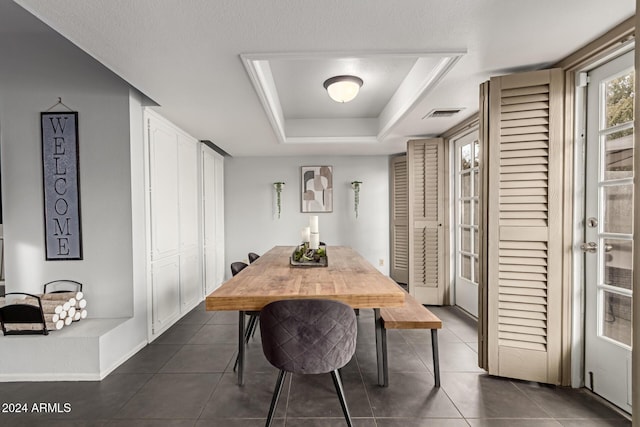 dining room featuring a tray ceiling and dark tile patterned floors