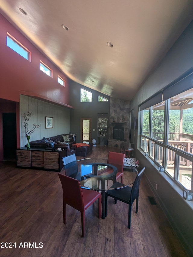 dining room featuring wood-type flooring, a stone fireplace, and lofted ceiling