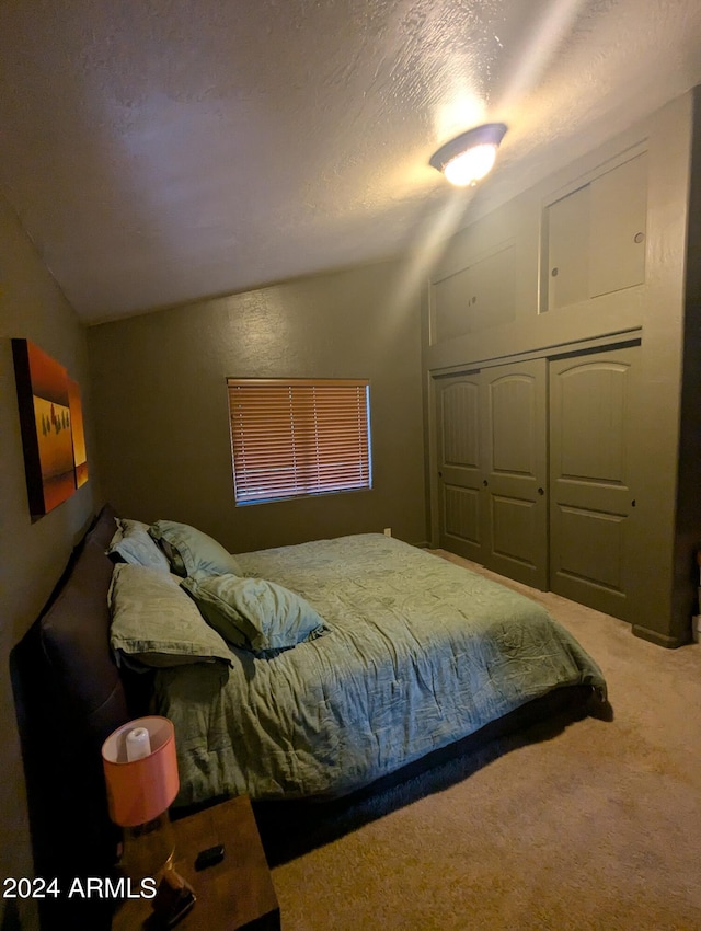 bedroom featuring carpet, a closet, vaulted ceiling, and a textured ceiling