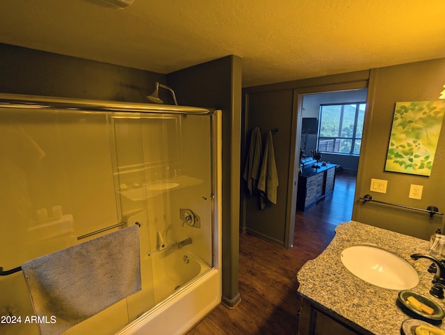 bathroom featuring a textured ceiling, bath / shower combo with glass door, vanity, and hardwood / wood-style flooring