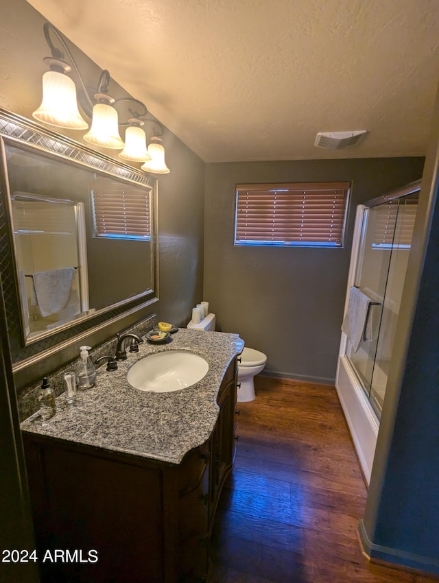 full bathroom with enclosed tub / shower combo, vanity, a textured ceiling, hardwood / wood-style flooring, and toilet