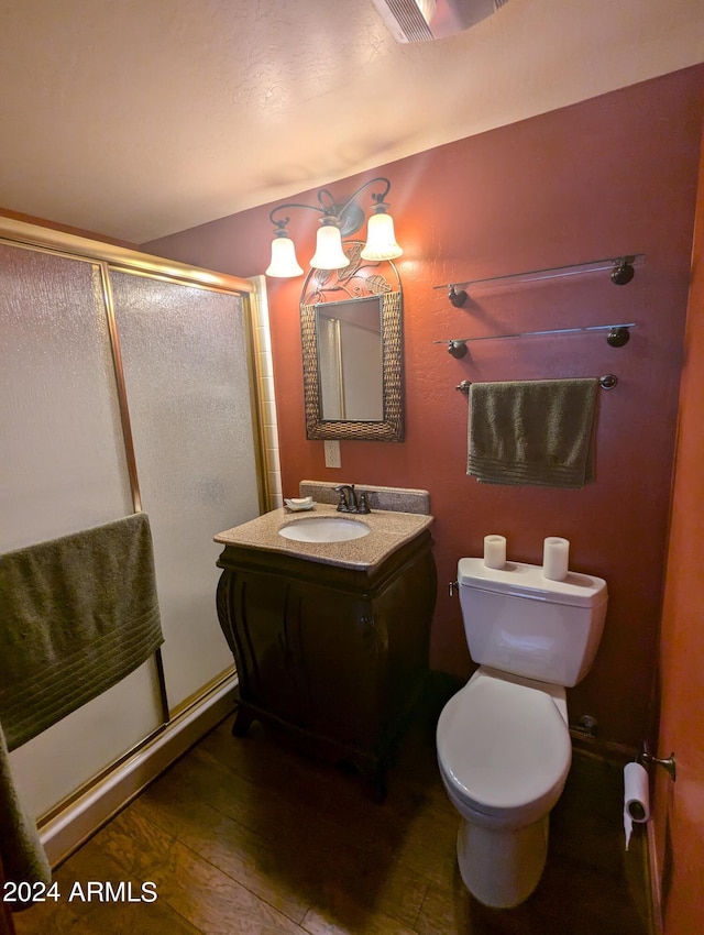 bathroom featuring walk in shower, hardwood / wood-style floors, vanity, and toilet