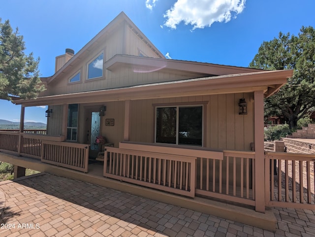 back of property featuring covered porch