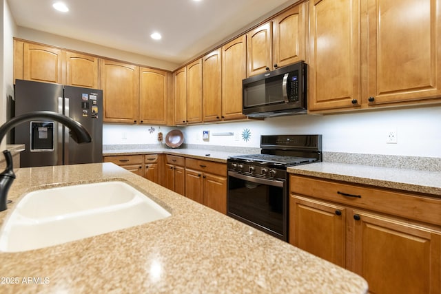 kitchen featuring light stone countertops, sink, and black appliances