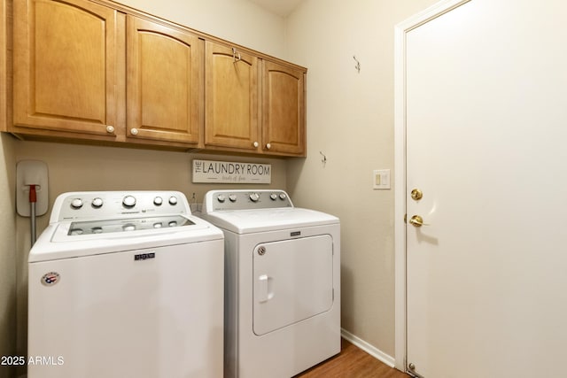 clothes washing area with separate washer and dryer, cabinets, and light hardwood / wood-style floors