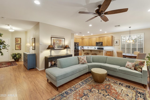 living room with ceiling fan and light hardwood / wood-style flooring