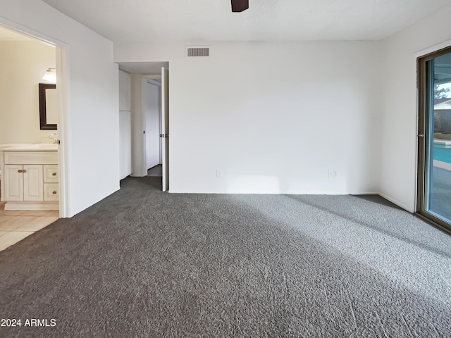 interior space with ensuite bath, ceiling fan, and dark carpet