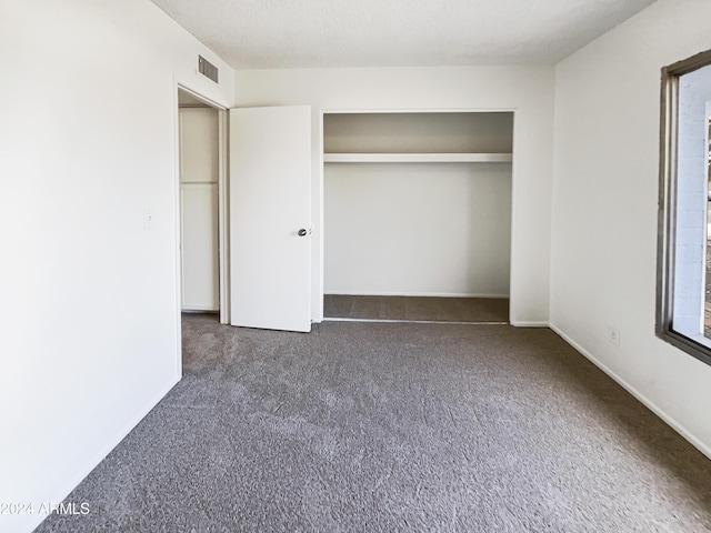 unfurnished bedroom featuring dark colored carpet and a closet