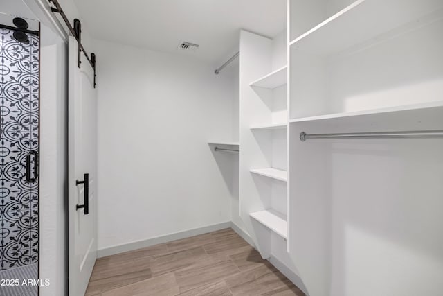 19401 W Flower St, Litchfield Park, AZ 85340 - spacious closet featuring a barn door and light wood-style flooring
