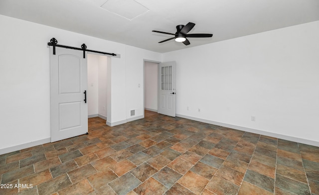 19401 W Flower St, Litchfield Park, AZ 85340 - unfurnished bedroom with stone finish flooring, a barn door, baseboards, and a ceiling fan