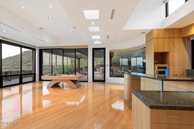 interior space with light hardwood / wood-style flooring, oven, dark stone countertops, billiards, and floor to ceiling windows